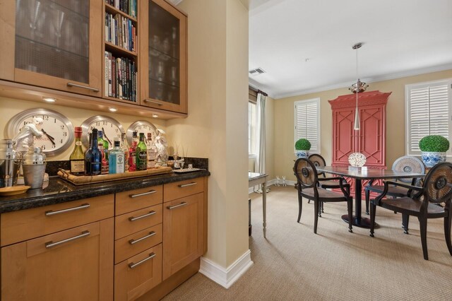 bar featuring dark stone counters, pendant lighting, light carpet, and ornamental molding