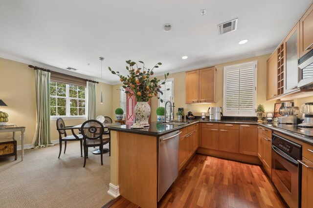 kitchen featuring kitchen peninsula, hardwood / wood-style flooring, sink, ornamental molding, and appliances with stainless steel finishes