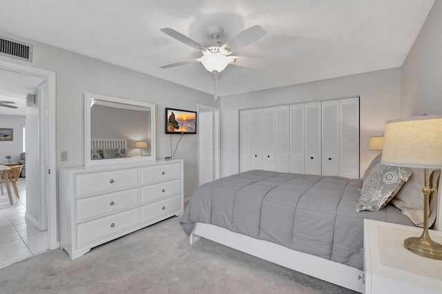 bedroom featuring light carpet, a closet, a textured ceiling, and ceiling fan