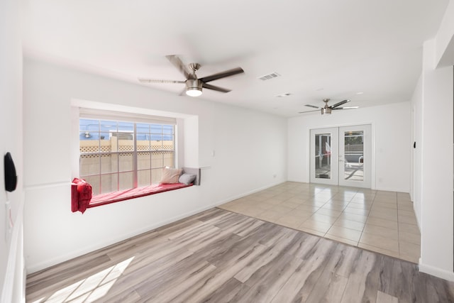 empty room with baseboards, visible vents, a ceiling fan, wood finished floors, and french doors