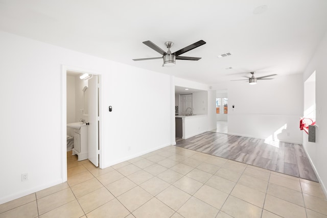 unfurnished room featuring light tile patterned floors, baseboards, visible vents, and a ceiling fan