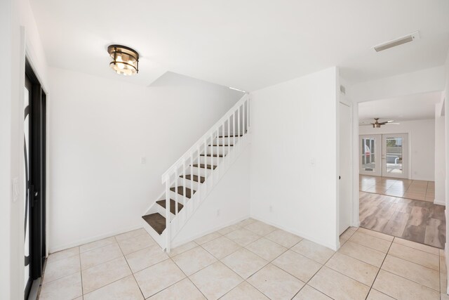 stairway with light hardwood / wood-style flooring and ceiling fan