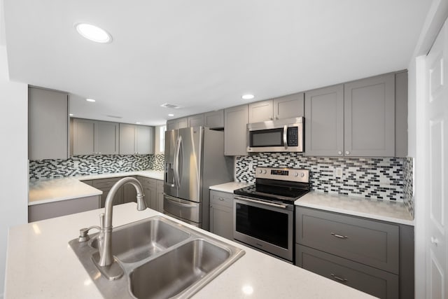 kitchen with stainless steel appliances, a sink, and gray cabinetry