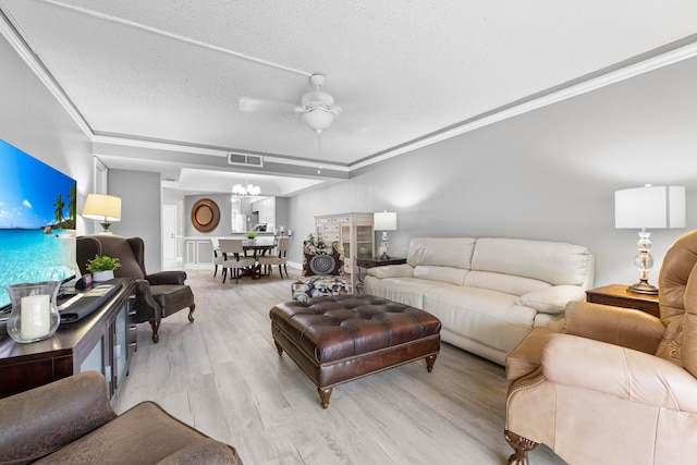 living room featuring a textured ceiling, light hardwood / wood-style flooring, ceiling fan with notable chandelier, and crown molding