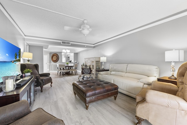 living room with a textured ceiling, ceiling fan with notable chandelier, visible vents, light wood-style floors, and crown molding