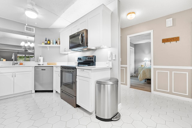 kitchen featuring white cabinetry, light wood-type flooring, ceiling fan with notable chandelier, stainless steel appliances, and sink