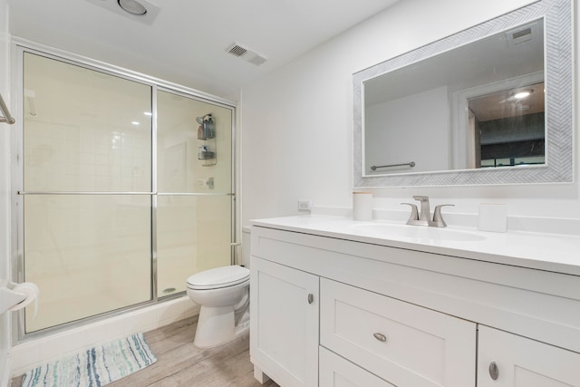 bathroom with a shower with shower door, vanity, wood-type flooring, and toilet