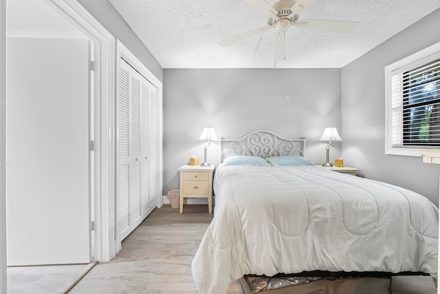 bedroom featuring a textured ceiling, light wood-type flooring, ceiling fan, and a closet