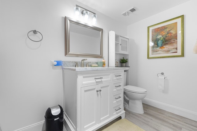 bathroom featuring wood-type flooring, toilet, and vanity