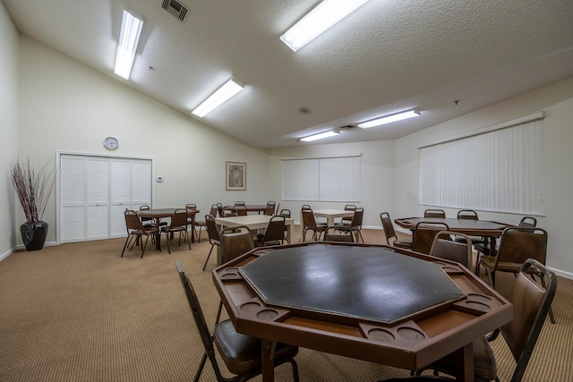 dining space featuring carpet, a textured ceiling, and vaulted ceiling