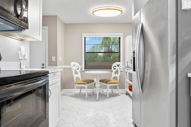 kitchen featuring white cabinetry, light tile patterned flooring, a textured ceiling, and stainless steel appliances