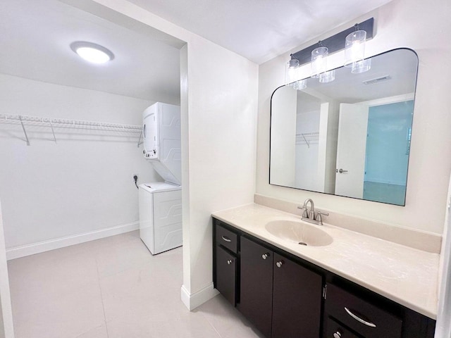 bathroom featuring stacked washing maching and dryer, tile patterned flooring, and vanity