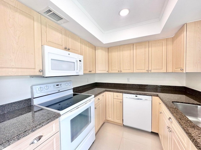 kitchen with light brown cabinets, a tray ceiling, dark stone counters, and white appliances