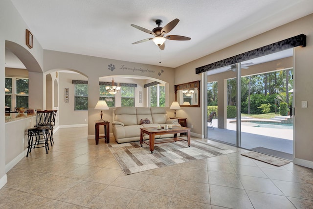 living room with ceiling fan with notable chandelier, a textured ceiling, and light tile patterned floors