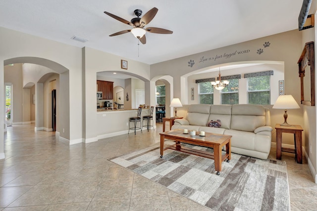 living room with ceiling fan with notable chandelier