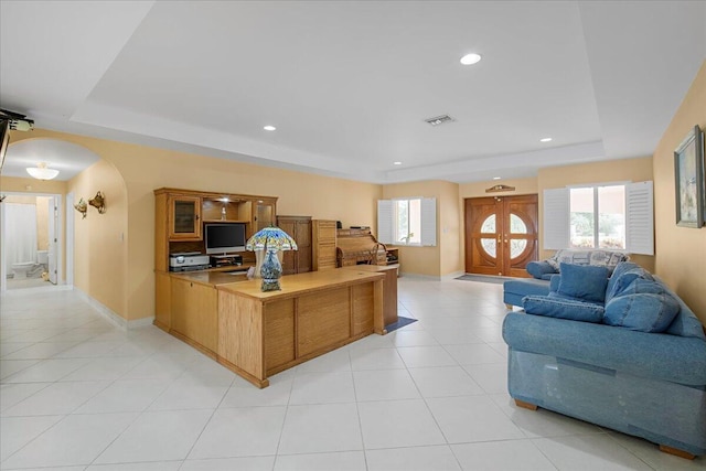 office area with light tile patterned floors and a tray ceiling