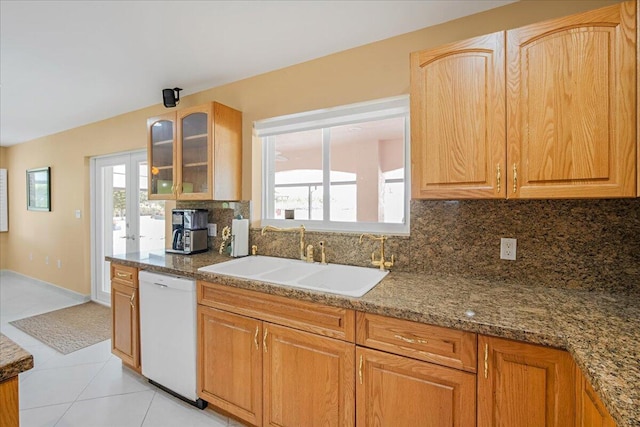 kitchen featuring white dishwasher, tasteful backsplash, stone countertops, light tile patterned floors, and sink