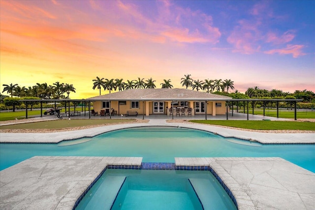 pool at dusk with a patio and a lawn