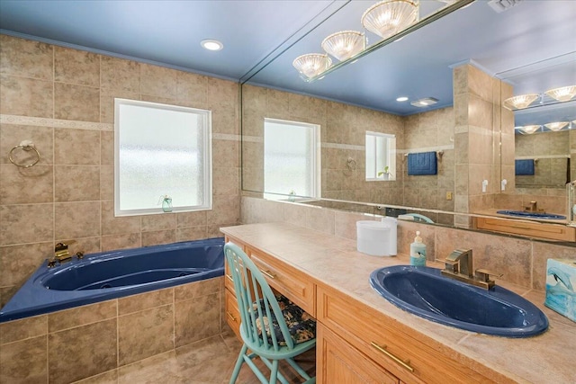 bathroom with tiled bath, tile walls, vanity, and decorative backsplash