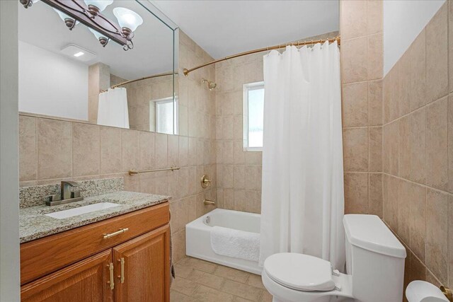 full bathroom featuring tile walls, tile patterned flooring, shower / bathtub combination with curtain, toilet, and vanity