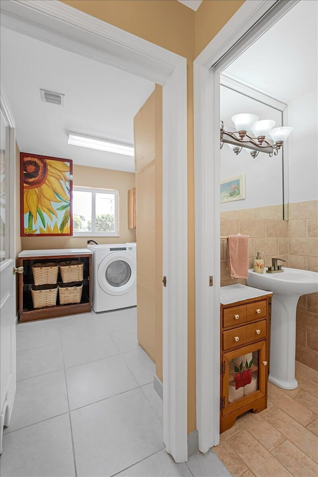 clothes washing area featuring a chandelier, tile walls, cabinets, and light tile patterned floors