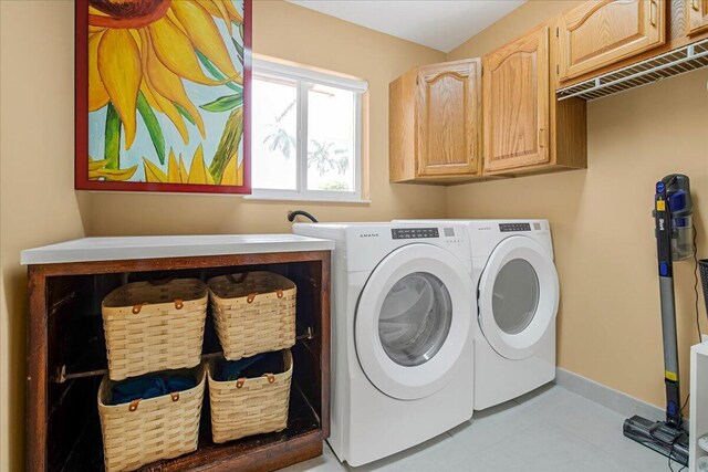 laundry room with cabinets, washer and dryer, and light tile patterned floors