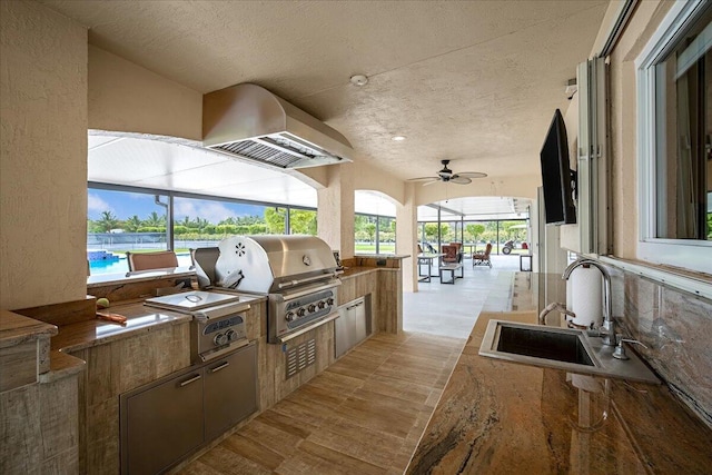 exterior space with an outdoor kitchen, sink, a grill, and a lanai