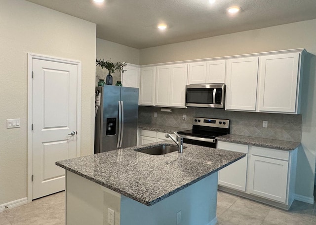 kitchen featuring backsplash, sink, a kitchen island with sink, light tile patterned floors, and stainless steel appliances