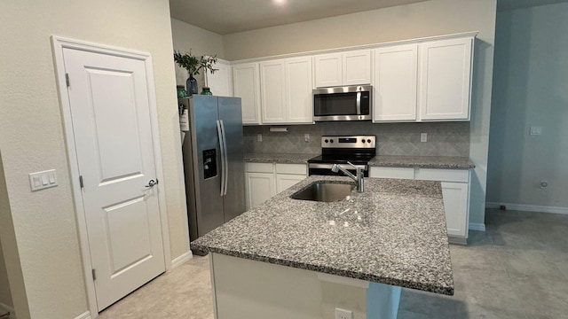 kitchen with white cabinetry, appliances with stainless steel finishes, tasteful backsplash, and an island with sink