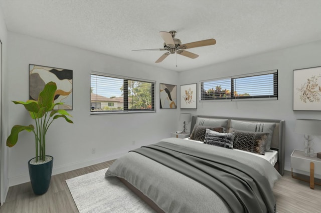 bedroom featuring ceiling fan, wood-type flooring, and a textured ceiling