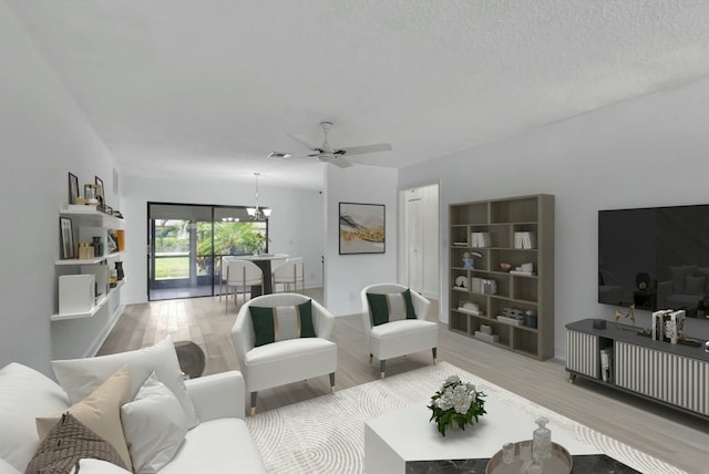 living room with ceiling fan with notable chandelier, a textured ceiling, and light wood-type flooring