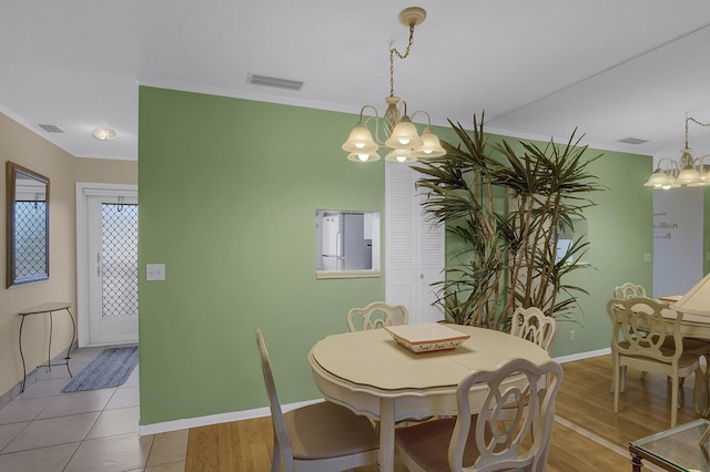 dining room featuring a notable chandelier, ornamental molding, and light hardwood / wood-style flooring