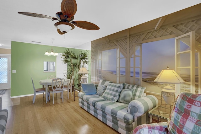 living room featuring ceiling fan with notable chandelier and light wood-type flooring