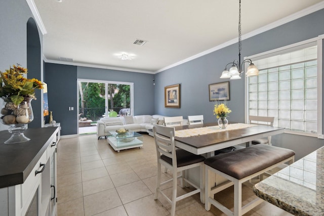 dining space featuring crown molding, an inviting chandelier, and light tile patterned floors