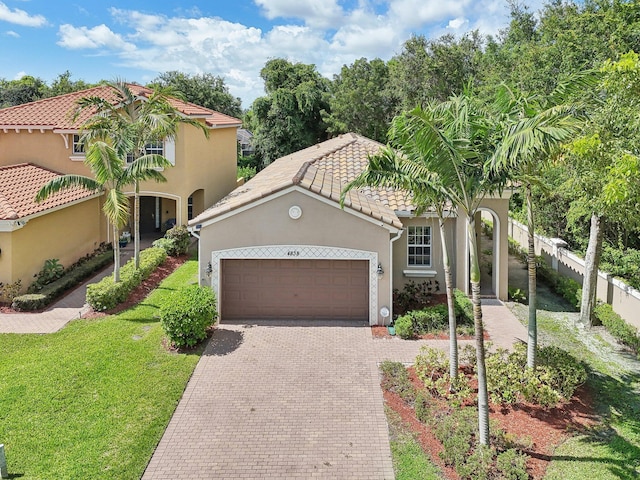 mediterranean / spanish-style home featuring a garage and a front lawn