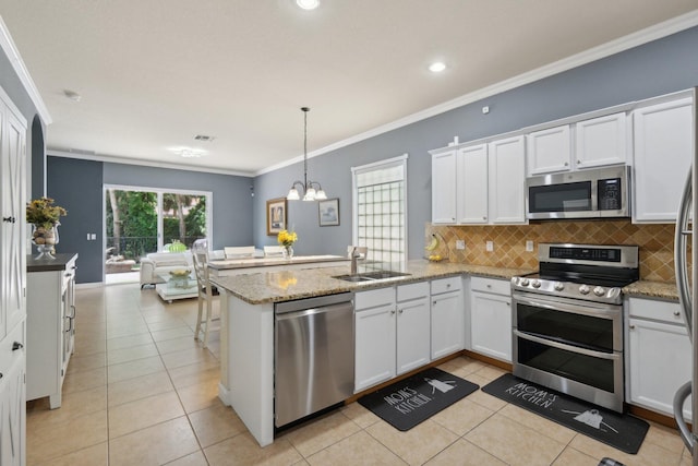 kitchen with appliances with stainless steel finishes, pendant lighting, white cabinets, and sink