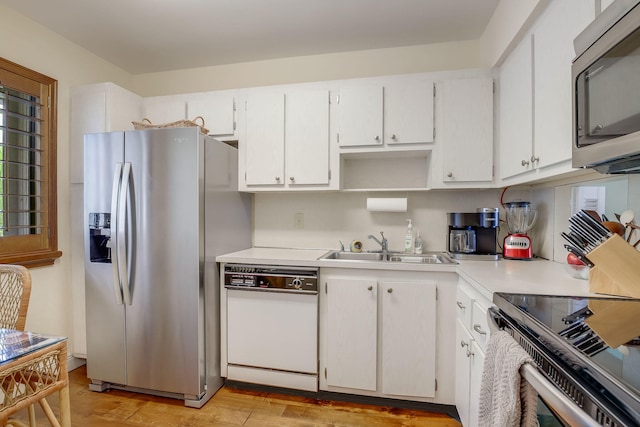 kitchen with appliances with stainless steel finishes, light hardwood / wood-style flooring, white cabinets, and sink