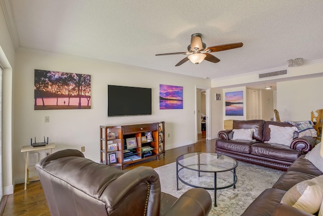 living room featuring wood-type flooring, a textured ceiling, ornamental molding, and ceiling fan