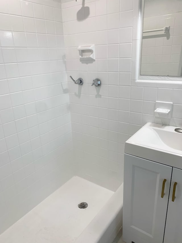 bathroom featuring tiled shower and vanity