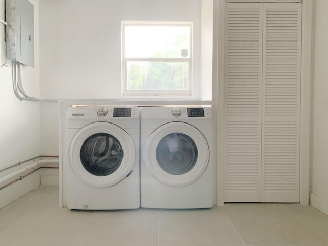 washroom with light tile patterned flooring, washing machine and clothes dryer, and electric panel