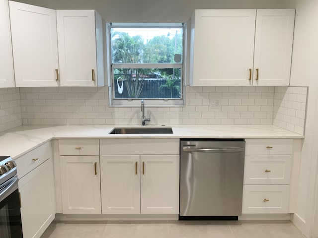 kitchen with stainless steel appliances, sink, white cabinets, and light stone counters