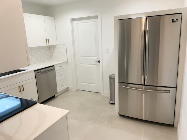 kitchen featuring light tile patterned floors, sink, appliances with stainless steel finishes, white cabinets, and decorative backsplash