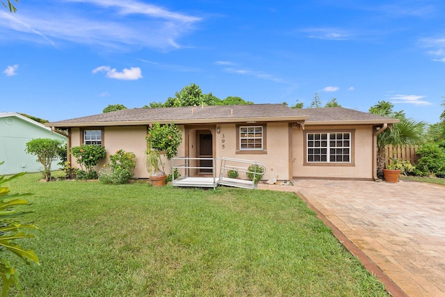 ranch-style home featuring a front lawn and a patio