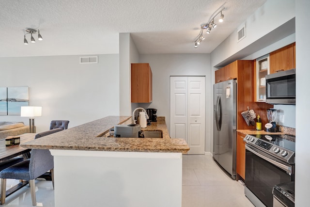 kitchen featuring a textured ceiling, kitchen peninsula, track lighting, appliances with stainless steel finishes, and sink