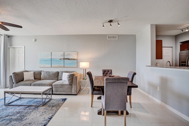 tiled living room featuring a textured ceiling, ceiling fan, and track lighting