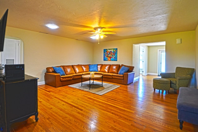 living room with hardwood / wood-style flooring, a textured ceiling, and ceiling fan