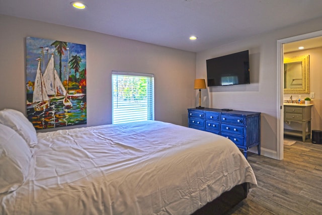 bedroom with connected bathroom, dark hardwood / wood-style flooring, and sink