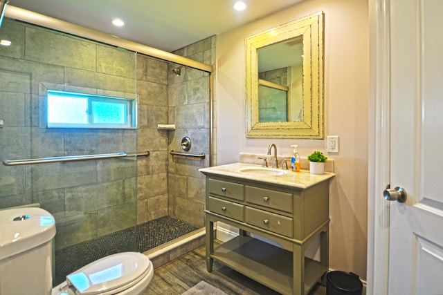 bathroom featuring wood-type flooring, toilet, vanity, and an enclosed shower