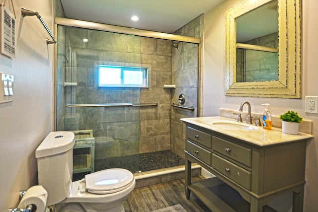 bathroom with wood-type flooring, a shower with shower door, toilet, and vanity