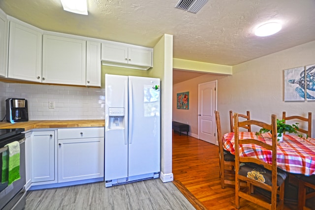 kitchen with tasteful backsplash, wood counters, white cabinets, light hardwood / wood-style floors, and white refrigerator with ice dispenser